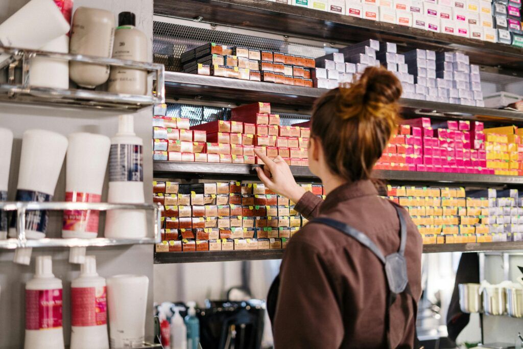 A hairstylist organizing vibrant hair color boxes on a shelf in a beauty salon.easy to do skin care .
