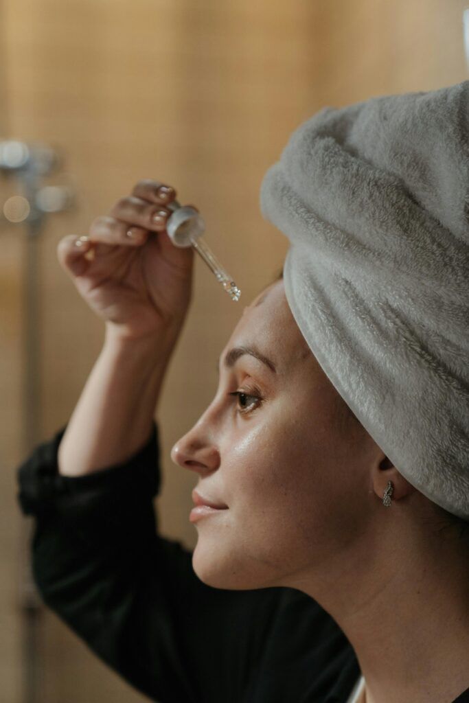 Close-up side view of a woman applying skincare serum with a dropper, promoting beauty routine.best skin care products .